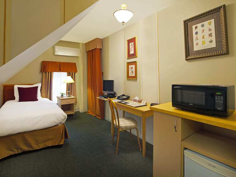 A spacious guest room with a single bed, a desk, and a microwave