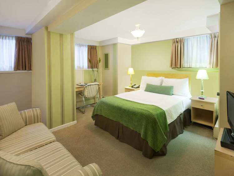 A studio guest room with one double bed, a sofa, and a TV
