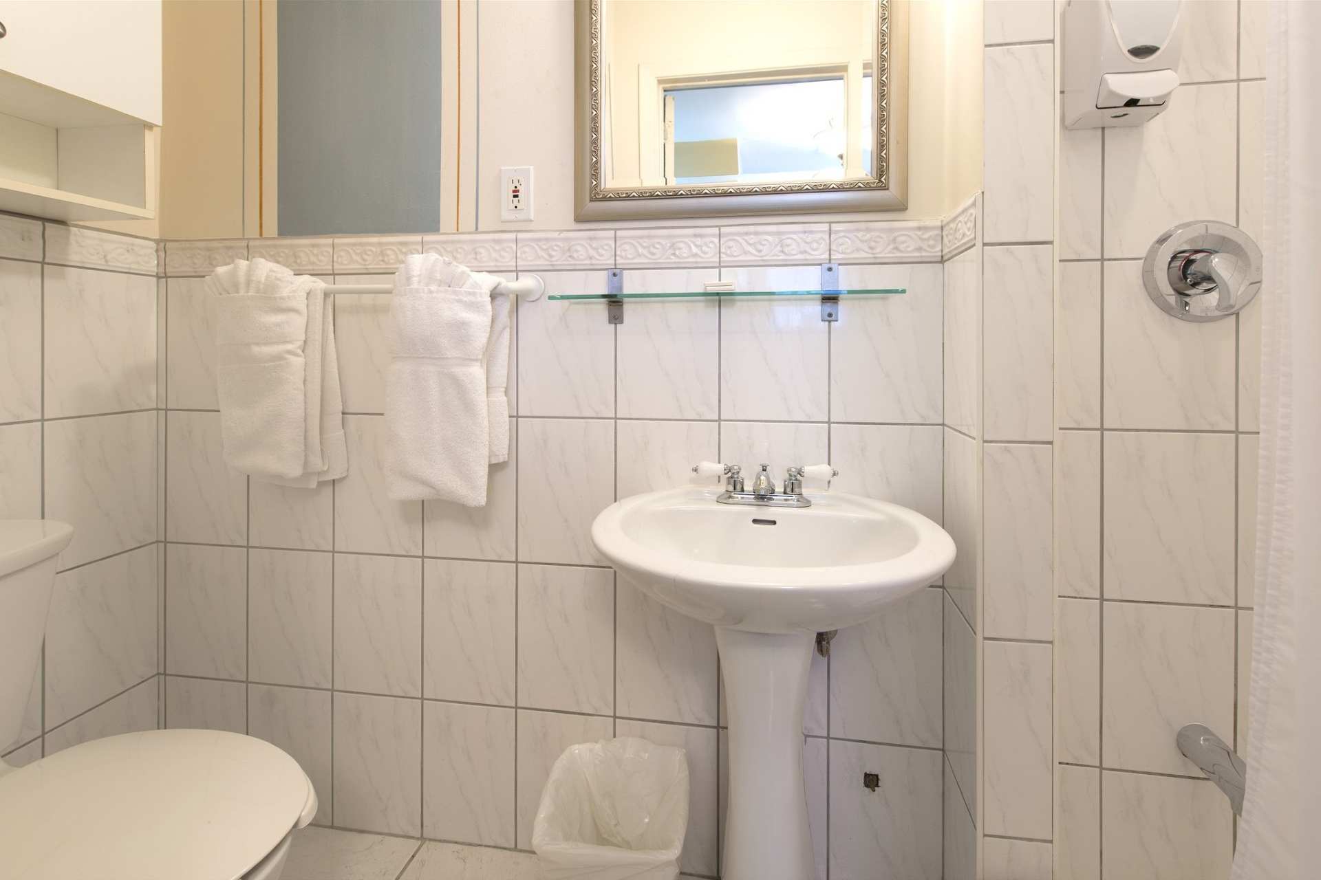 A bathroom with a sink, toilet, and hanging towels