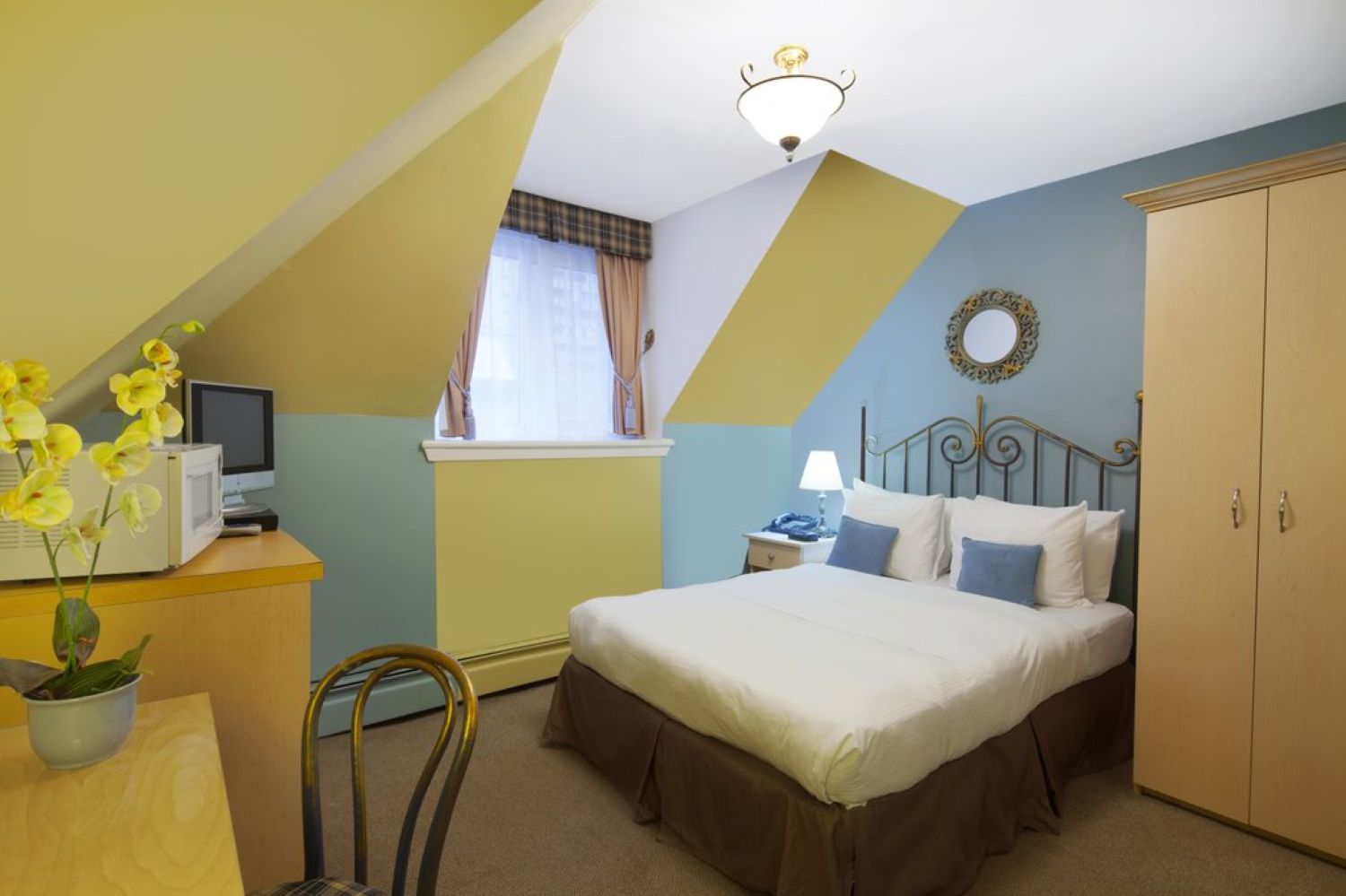 A room with a double bed with white and blue bedding