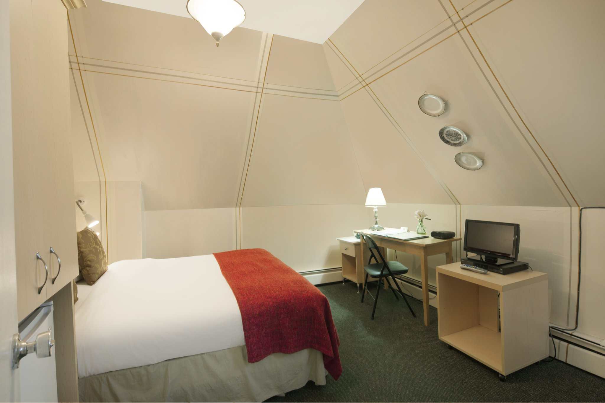 A guest room with a double bed, a small TV, and a desk